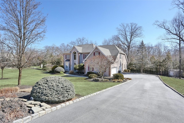 exterior space with aphalt driveway, a front yard, and a garage