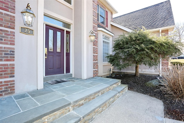 property entrance featuring a shingled roof and brick siding