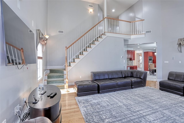 living area with stairs, visible vents, and wood finished floors