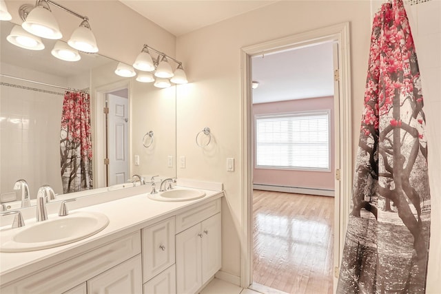 bathroom featuring double vanity, a baseboard radiator, a sink, and wood finished floors