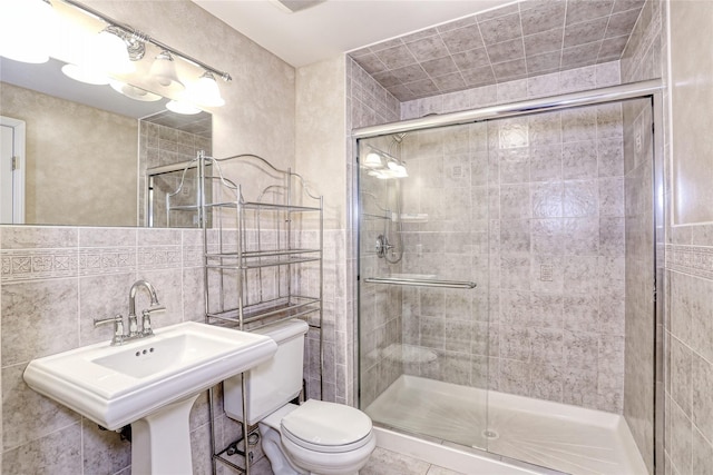 full bath featuring toilet, a stall shower, and tile walls