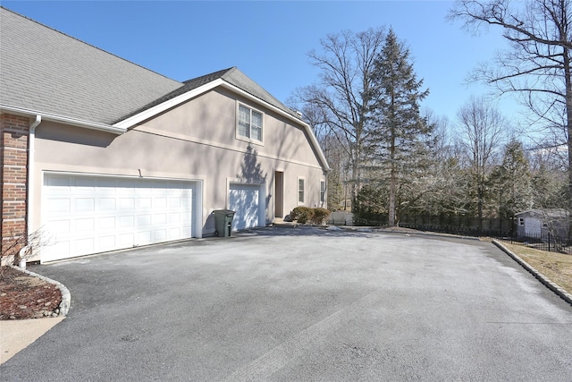 view of side of home with driveway, a shingled roof, and brick siding