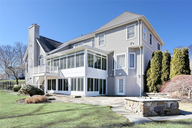 rear view of house with a sunroom, stairs, a yard, a chimney, and a patio area