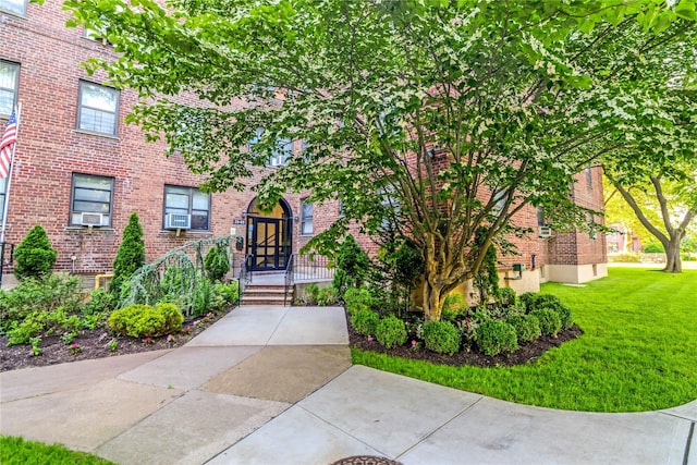 view of front of house with brick siding, a front yard, and cooling unit