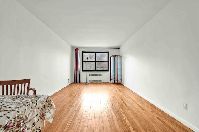 unfurnished bedroom featuring light wood-type flooring, radiator heating unit, and baseboards