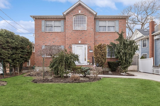 view of front of house featuring brick siding, a front lawn, and fence