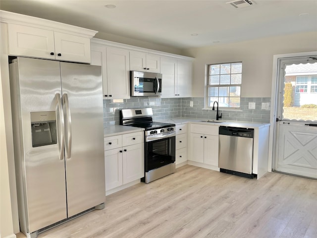 kitchen with a sink, white cabinetry, stainless steel appliances, and light countertops