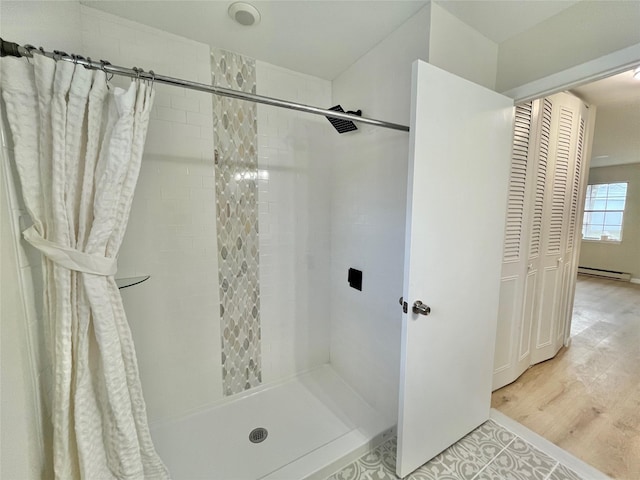 full bathroom with a stall shower, baseboard heating, and wood finished floors