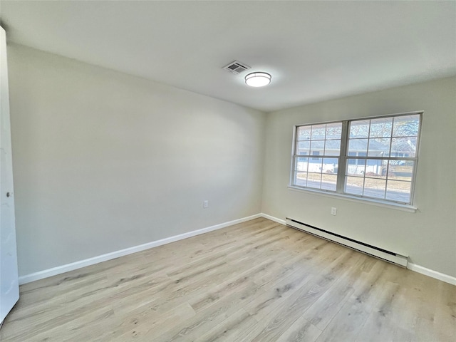 unfurnished room with baseboards, baseboard heating, visible vents, and light wood-style floors