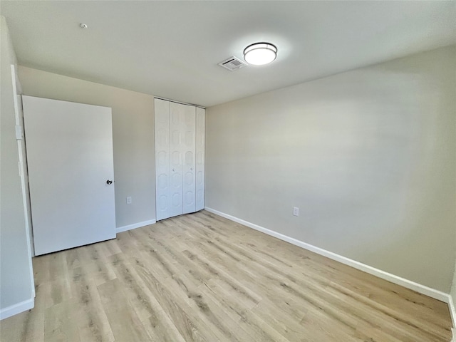 unfurnished bedroom featuring a closet, baseboards, visible vents, and light wood finished floors