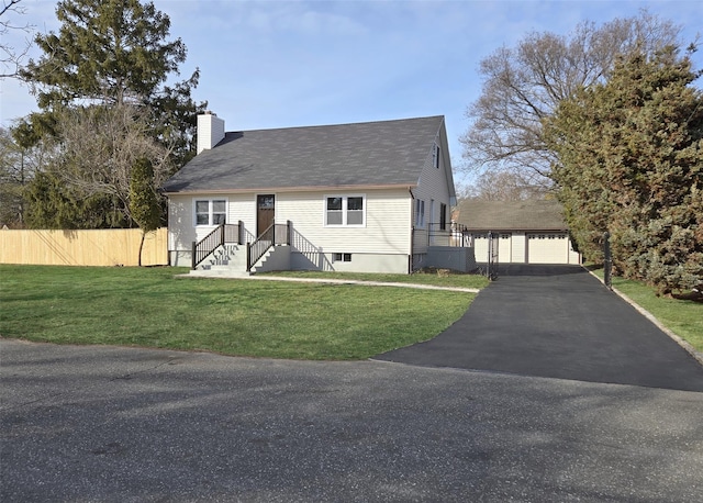 view of front of home featuring a chimney, fence, a detached garage, and a front yard