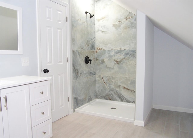 bathroom featuring vaulted ceiling, a stall shower, vanity, and baseboards