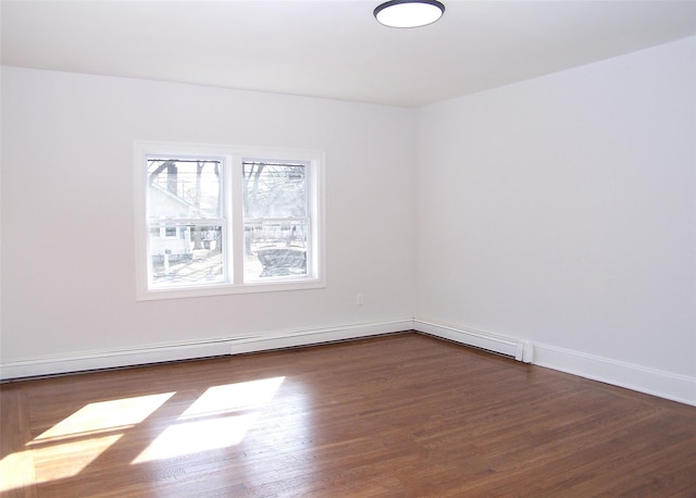 empty room featuring dark wood-style floors, baseboards, and a baseboard heating unit