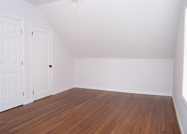 additional living space with dark wood-style floors, vaulted ceiling, and baseboards