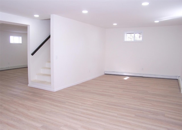 basement with a baseboard heating unit, recessed lighting, light wood finished floors, and stairs