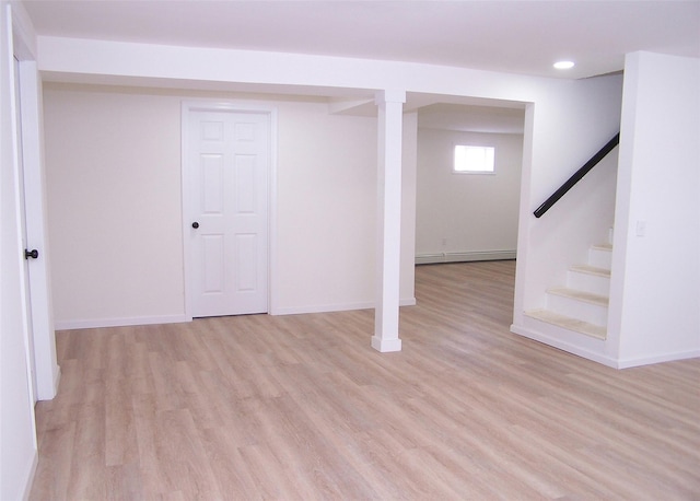 basement featuring stairs, light wood finished floors, baseboard heating, and baseboards