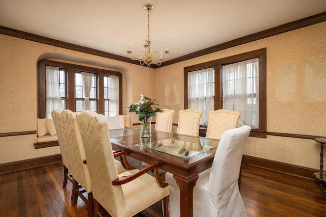 dining room with baseboards, ornamental molding, wallpapered walls, dark wood finished floors, and an inviting chandelier