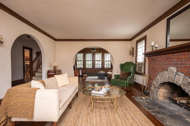 living room featuring baseboards, arched walkways, stairway, wood finished floors, and a fireplace