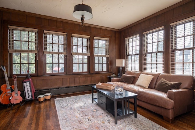 living area featuring a baseboard heating unit, ornamental molding, wood finished floors, and wooden walls