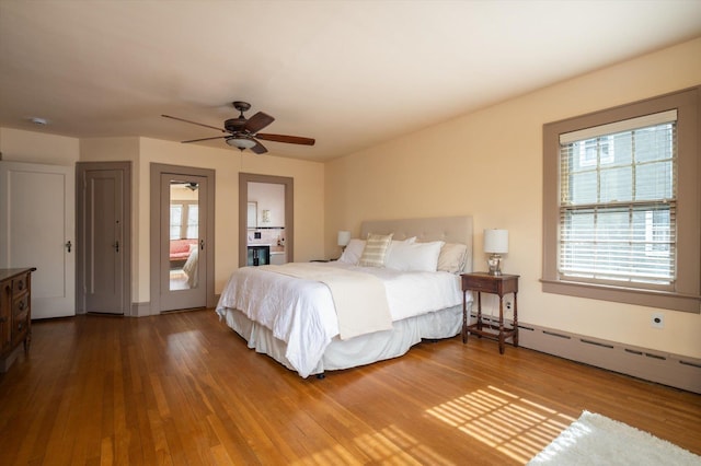 bedroom featuring a baseboard heating unit, a ceiling fan, and wood finished floors