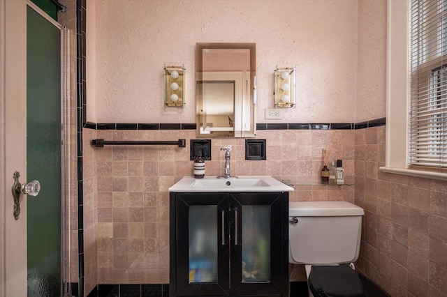 bathroom featuring a textured wall, vanity, toilet, and a shower stall