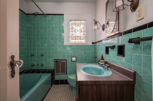 full bathroom featuring tile walls, heating unit, toilet, vanity, and tile patterned flooring