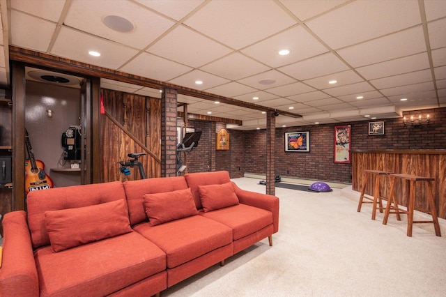 carpeted living room with brick wall, a bar, a paneled ceiling, and recessed lighting