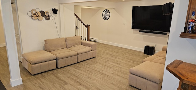 living area with stairs, baseboard heating, baseboards, and wood finished floors