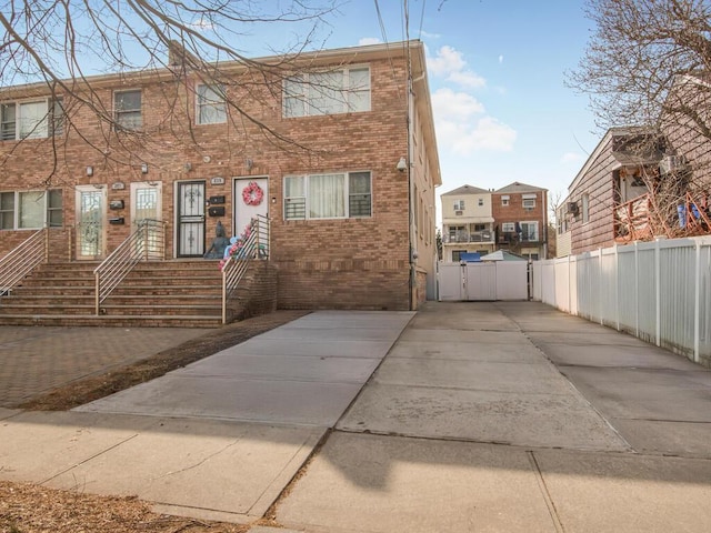 townhome / multi-family property featuring brick siding, fence, and a gate