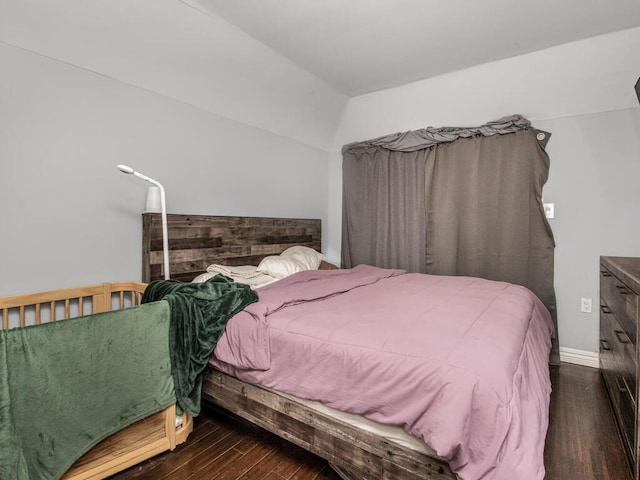 bedroom featuring lofted ceiling, wood finished floors, and baseboards