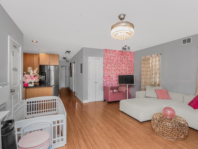 living room featuring baseboards, visible vents, light wood-style floors, a chandelier, and recessed lighting