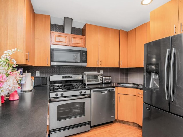 kitchen with a toaster, appliances with stainless steel finishes, dark countertops, and decorative backsplash