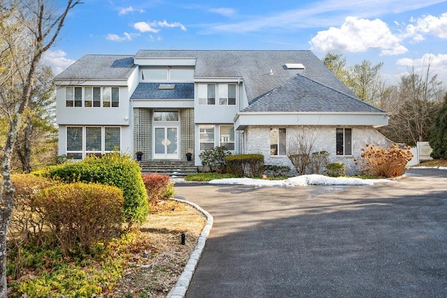 view of front of property with stone siding and roof with shingles