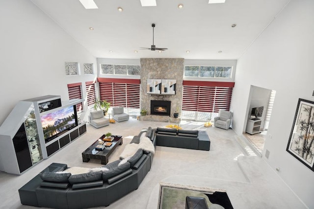 living room with a stone fireplace, a high ceiling, a skylight, and recessed lighting