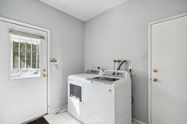 laundry room featuring washing machine and clothes dryer, light tile patterned floors, visible vents, laundry area, and baseboards