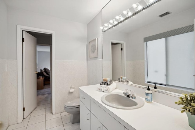 bathroom featuring tile walls, visible vents, toilet, vanity, and tile patterned flooring