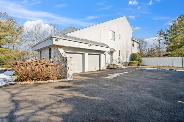 view of property exterior featuring a garage, fence, and driveway