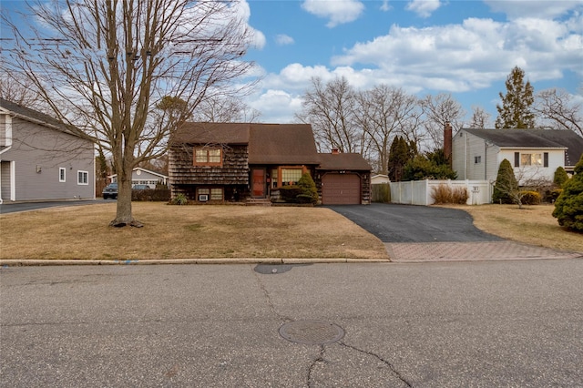 view of front of home with a garage, driveway, a front lawn, and fence