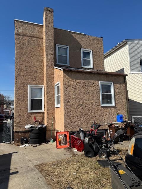 rear view of house with a patio area, fence, and stucco siding