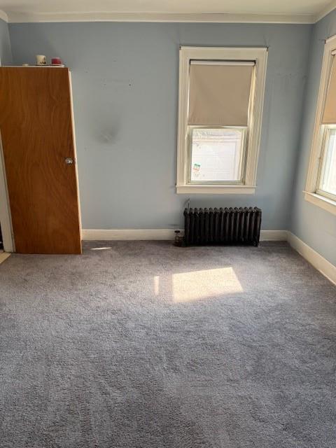 empty room with radiator, baseboards, and carpet floors