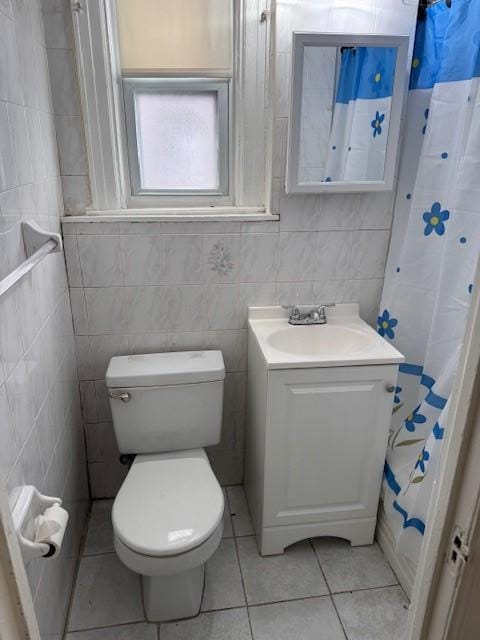 full bathroom with toilet, tile patterned flooring, vanity, and tile walls