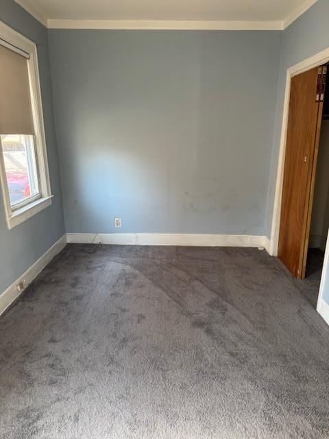 unfurnished room featuring ornamental molding, dark colored carpet, and baseboards