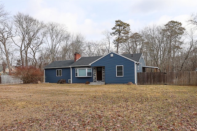 ranch-style house featuring a chimney, a front yard, and fence