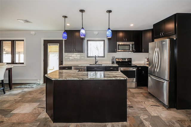 kitchen with appliances with stainless steel finishes, decorative light fixtures, a kitchen island, and light stone countertops