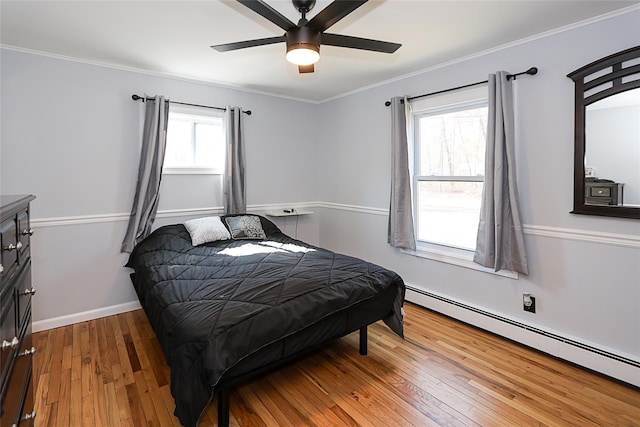 bedroom featuring crown molding, hardwood / wood-style floors, baseboard heating, ceiling fan, and baseboards