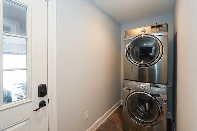 washroom with stacked washer and dryer, laundry area, and baseboards