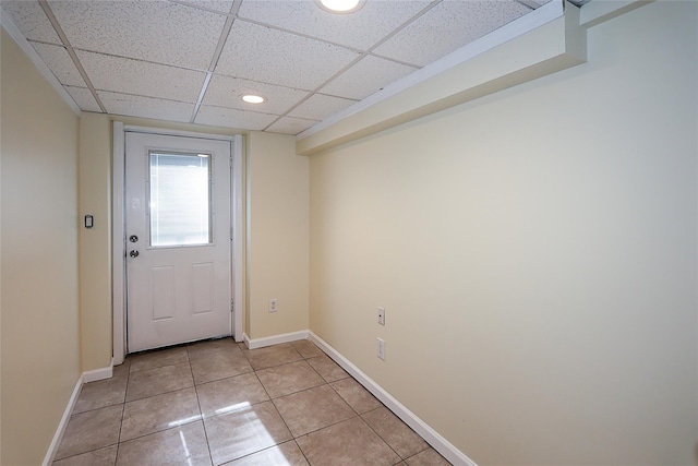 doorway to outside featuring light tile patterned floors, a paneled ceiling, and baseboards