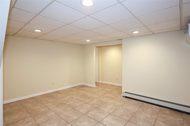 empty room with a baseboard heating unit, recessed lighting, a drop ceiling, and baseboards