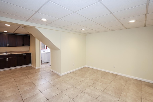 interior space with baseboards, a drop ceiling, a sink, and recessed lighting