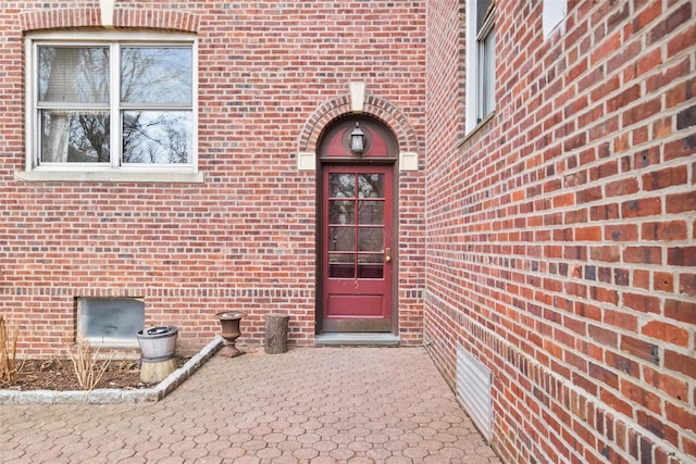 doorway to property featuring crawl space, a patio area, and brick siding